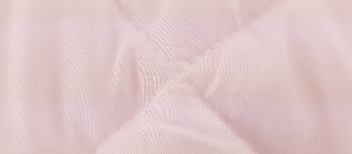 zbliżenie na pikowaną tkaninę w kolorze różoym która została użyta do produkcji kołdry termo